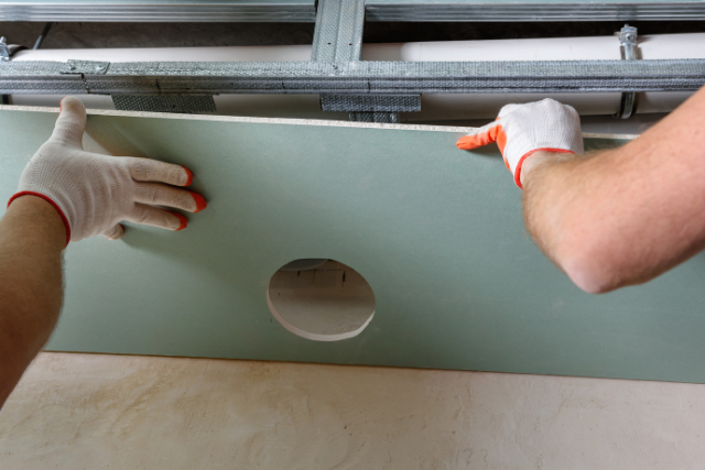 Drywall Installation by two workers with gloves on