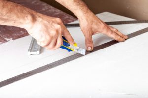 Portland Drywall repair by worker with a knife and a ruler